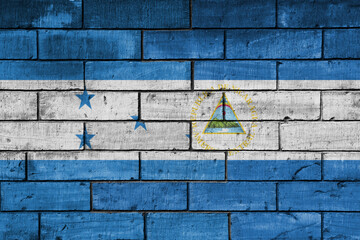 colourful painted big national flag of nicaragua and flag of honduras on a massive old brick wall background. concept