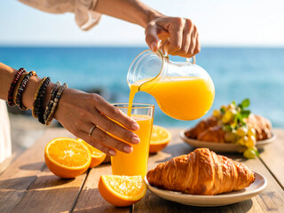 A woman's hands are pouring freshly squeezed orange juice into a pitcher on a rustic wooden table. In the background, a beach, carefree holiday time.