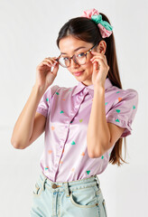 Young woman adjusting glasses while posing in colorful shirt  