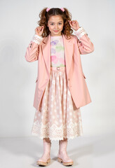 Young girl posing in fashionable outfit with pink blazer and skirt  