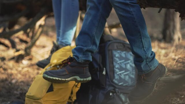 Legs of hikers rest on pause in nature. restful tree moment. Woodland respite legs by sturdy tree. Legs tree trunk support hiking interlude. Hiking boots dangle legs rest on tree. boots hiking harmony