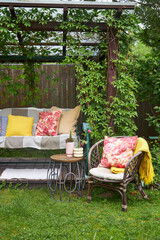 A view of garden swings with pink textile decor and seasonal flowers around