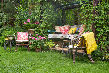 A view of garden swings with pink textile decor and seasonal flowers around