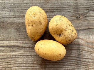 Three raw potatoes on a wooden surface