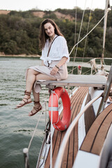 Beautiful young girl in a white shirt and hat on a yacht at sea in summer.