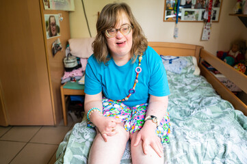 Portrait of a 42 yo happy woman with Down Syndrome in her sleeping room in Tienen, Flemish Brabant...