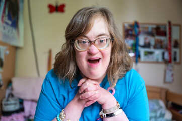Portrait of a 42 yo happy woman with Down Syndrome in her sleeping room in Tienen, Flemish Brabant...