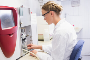 Analytical instrument processing samples at bright lab bench, with red housing and clear vials