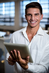 Tablet is being held in modern office workspace, with desks chairs and window blinds