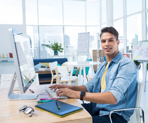 Mid adult man working on graphics tablet and desktop computer at modern office desk, copy space