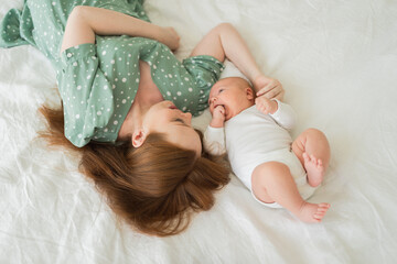 Happy family at home. Mother holding little baby toddler child feeding milk from bottle. Newborn Infant baby girl sucking eating drinking milk. Mom of breast feeding baby. Motherhood happy child