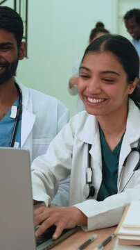 Vertical video. Multiethnic medical professionals celebrating collaborative success while analyzing data on laptop, showing teamwork, joy, and breakthrough in healthcare setting