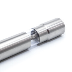 Detailed close-up of a sleek stainless steel manual grinder lying on a white background. The transparent section reveals chamber inside, highlighting the modern and functional kitchen design.