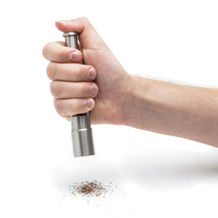 Close-up of a human hand using a stainless steel manual pepper grinder. Ground mixed pepper falls...