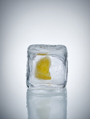A realistic side-view of a single ice cube with a frozen lemon wedge inside