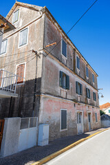 A quiet, sunlit street in the old town of Primosten, Croatia, lined with traditional stone buildings and Mediterranean charm.
