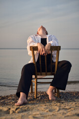 Young woman in relaxed pose, sitting on chair by calm beach, embodying serenity. Tranquil seascape...