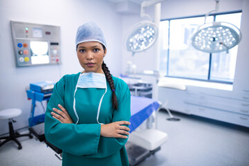 Overhead surgical lights shining on blue-draped operating table near trolley by city window in OR
