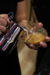 barista echando leche con espuma en una taza de café para elaborar un capuchino