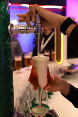 barman echando cerveza con espuma de un grifo de barril a una copa
