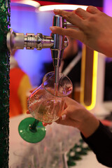 camarero echando cerveza a una copa desde el grifo de la barra