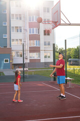 The father watches the ball hitting the ring. The family plays basketball