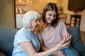 Volunteer and senior woman watching something on the phone