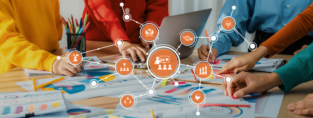 A diverse team collaborates in a bright workspace, engaging in brainstorming and digital planning,...