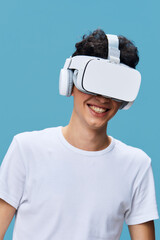 young man wearing virtual reality headset smiling with excitement against blue background, casual white t-shirt, technology and innovation concept, immersive experience