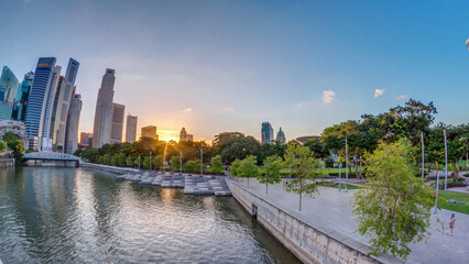 Obraz premium Sunset over Singapore skyscrapers skyline with white Anderson Bridge near esplanade park timelapse.