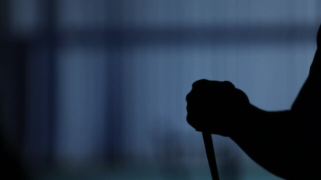 Silhouette of hands in action. They tap a stick, rub together, and clench fists, suggesting intense preparation or anticipation. A blurred blue background creates a moody, atmospheric setting.