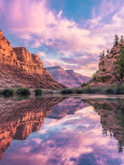 Sunset paints the canyon and river with vibrant hues, creating a stunning reflection.