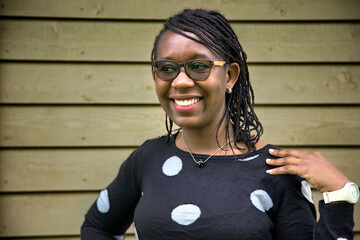 Smiling African Woman with Glasses and Braided Hair in Polka Dot Sweater Outdoors