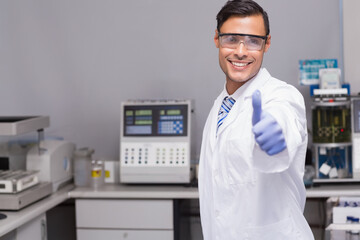 Male lab tech wearing lab coat operating analyzers in clinical lab with reagent bottles, copy space
