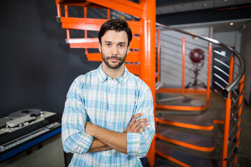 Professional audio mixing console glowing beside orange spiral stairs and industrial fan in studio