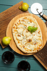Pizza with pear and mozzarella on a wooden board and two glasses of wine