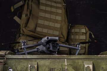 Drone with camera. Drone with three lenses. Quadcopter against the background of a military backpack.