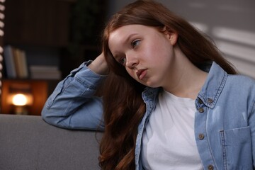 Sad teenage girl on sofa at home