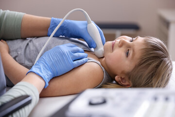 Sonographer conducting ultrasound examination of little girl's thyroid gland in clinic, closeup