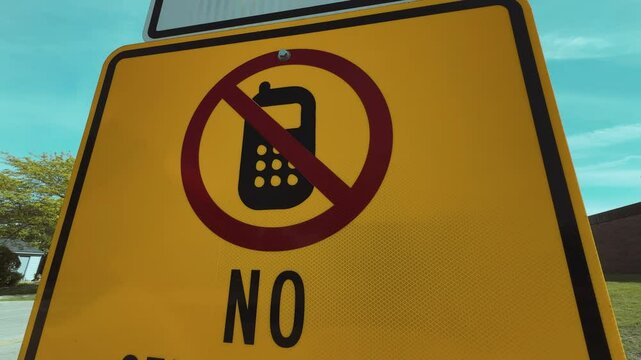 No Cell Phone Zone road sign on roadside, promoting safe driving and distraction-free zones. Traffic safety warning against mobile phone use in restricted driving areas