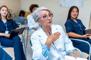 Senior doctor leading medical conference, explaining with hand gestures