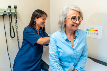 Doctor examining elderly woman's lungs during medical consultation