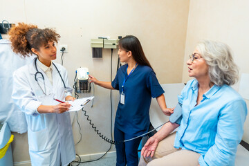 Doctor and nurse measuring blood pressure of senior patient