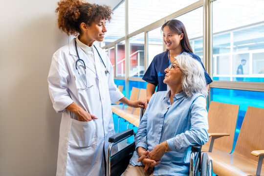 Doctor and nurse supporting senior woman in wheelchair at hospital