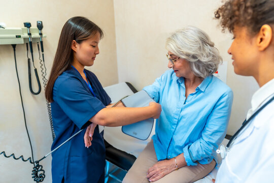 Nurse checking blood pressure of senior woman in medical clinic