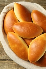 Many tasty baked patties on wooden table, closeup