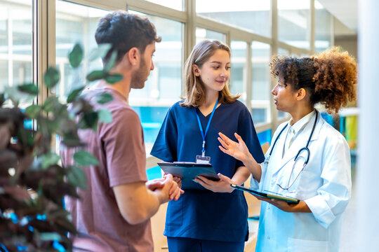 Doctors and nurse discussing patient's medical history in hospital corridor