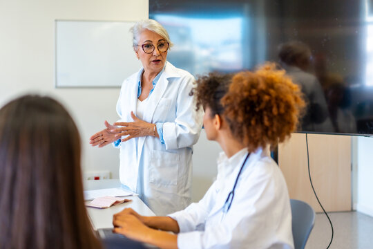 Senior doctor leading medical training for young professionals in hospital conference room