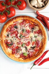Tasty pizza with thin smoked sausages and ingredients on white wooden table, flat lay