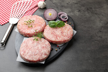 Fresh raw patties for burger and spices on grey table, closeup. Space for text
